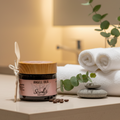 J of 'Angell Oils Coffee Scrubz product on a textured surface with coffee beans and decorative elements.